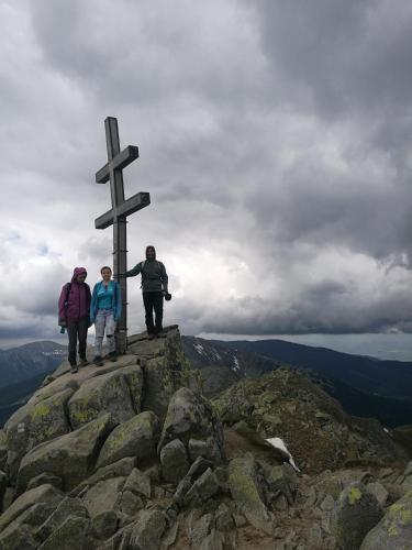tres personas de pie en la cima de una montaña con una cruz en Chata v záhrade, en Mýto pod Ďumbierom