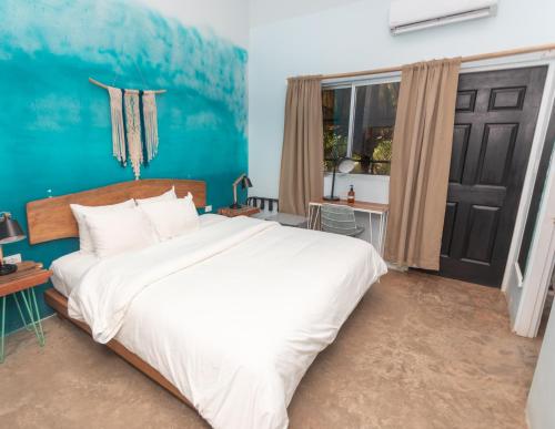 a bedroom with a white bed and a blue wall at Selina Santa Teresa North in Santa Teresa Beach