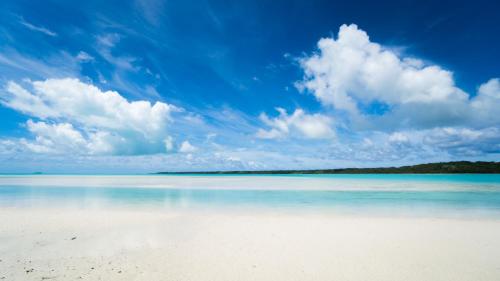 a view of a beach with a blue sky and clouds at Aitutaki Village in Arutanga