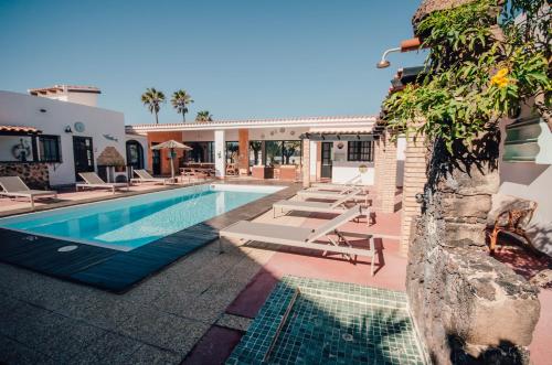 a swimming pool with lounge chairs next to a building at La Concha ADULTS ONLY CORRALEJO in Corralejo