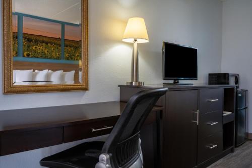 a room with a desk with a chair and a television at Days Inn by Wyndham Perrysburg Toledo in Perrysburg