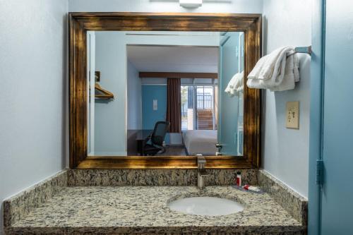 a mirror over a sink in a bathroom at Days Inn by Wyndham Perrysburg Toledo in Perrysburg