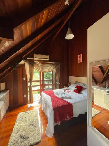 a bedroom with a bed and a large window at Chalé do Tabuleiro in Aguas Mornas
