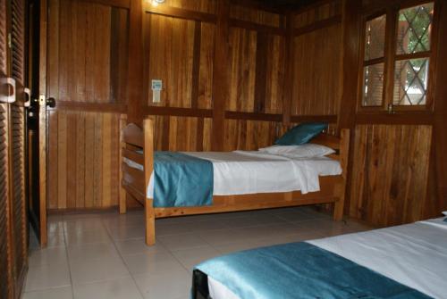 1 Schlafzimmer mit 2 Betten in einem Holzzimmer in der Unterkunft Chalet Condominio Campestre Rodadero Santa Marta wifi Piscina Amplia in Santa Marta