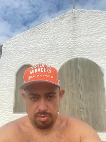 a man wearing a red hat with a sign on it at Chalé Palhano Beach in São Miguel dos Milagres