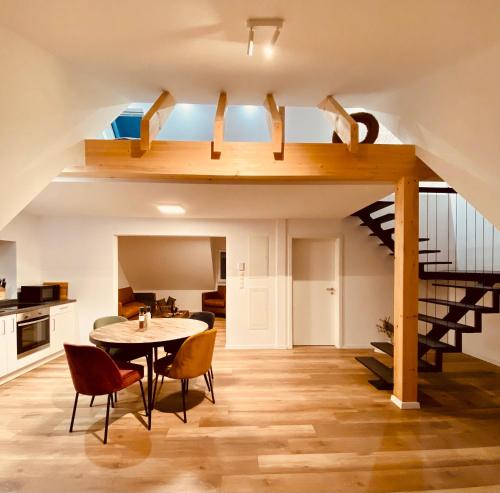 ein Wohnzimmer mit Tisch und Stühlen und einer Treppe in der Unterkunft Home Again Studios in Rutesheim