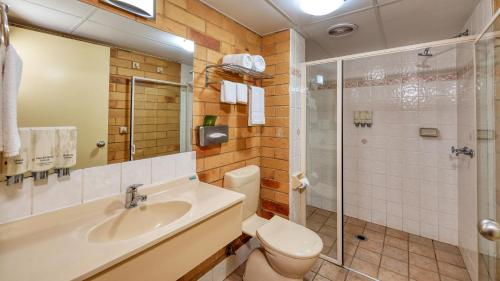 y baño con aseo, lavabo y ducha. en North Parkes Motel, en Parkes