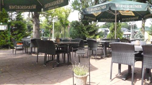 eine Gruppe von Tischen und Stühlen mit Sonnenschirmen in der Unterkunft Hotel und Restaurant Kranichsberg in Woltersdorf
