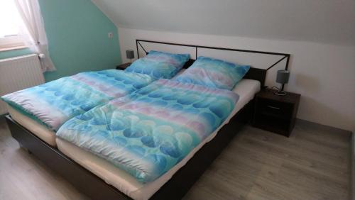 a large bed with a blue comforter and pillows at Ferienhaus Scheerer in Vöhl