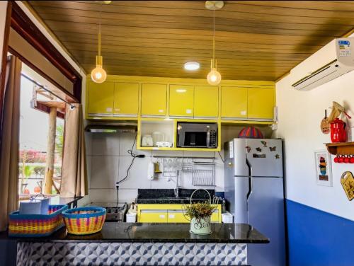 La cuisine est équipée de placards jaunes et d'un réfrigérateur. dans l'établissement Chaleville 1601 - Inigualável, à Luis Correia