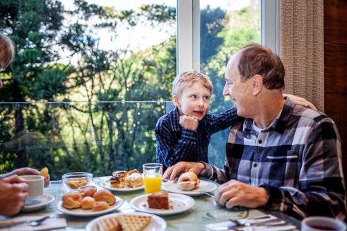 Een man en een kind zitten aan tafel te ontbijten. bij Villa Bella Hotel & SPA Gramado in Gramado