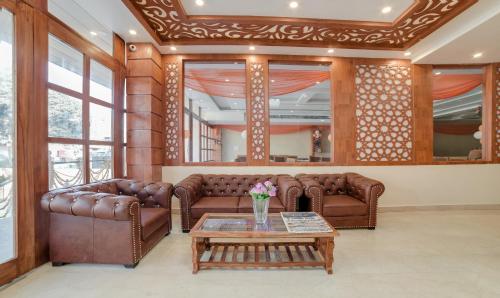 德拉敦Treebo G K Residency Near Dehradun Railway Station的客厅配有棕色皮沙发和桌子