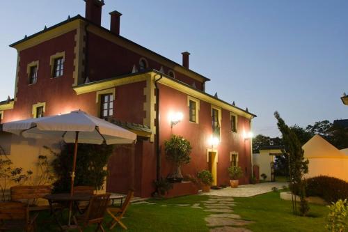 a house with a table and an umbrella in front of it at Casa do Merlo in Barreiros