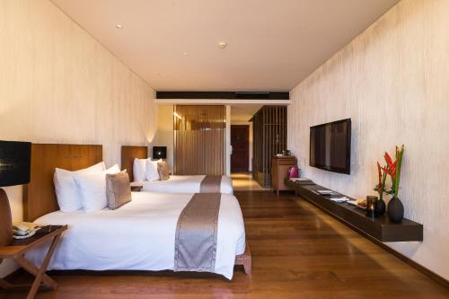a hotel room with a large bed and a tv at Hansar Samui Resort & Spa - SHA Extra Plus in Bophut 