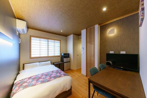 a bedroom with a bed and a desk and a television at YADOYA 雀 in Tokyo