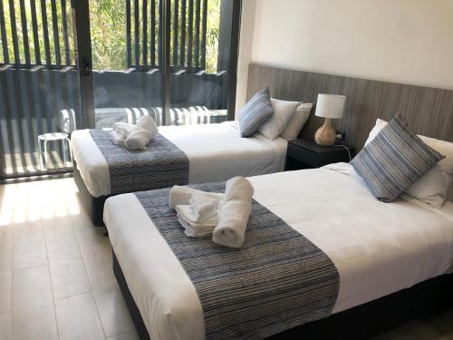 a hotel room with two beds with towels on them at Coogee Studio Apartments in Sydney