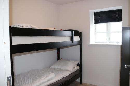 a black bunk bed in a room with a window at Søndervang, ferielejlighed in Svinninge