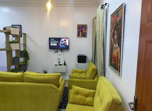 a living room with yellow couches and a tv at Cozy studio unit in lekki phase 1 - Kitchen, 24-7 light, wifi, Netflix in Lagos