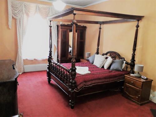 a bedroom with a canopy bed with a red carpet at Mintaro Hideaway in Mintaro