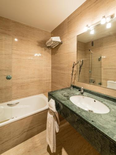 a bathroom with a tub and a sink and a bath tub at Hotel Ruta del Duero in La Cistérniga