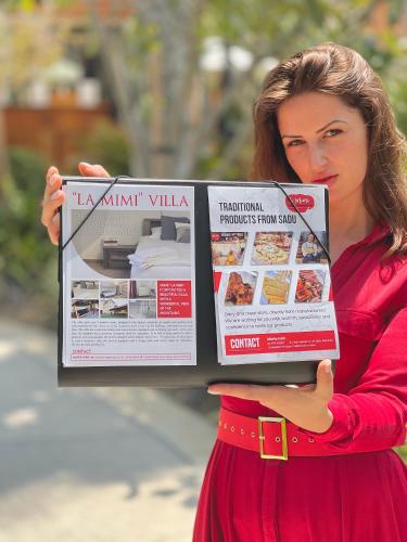 a woman in a red dress holding a magazine at La Mimi Villa in Sadu