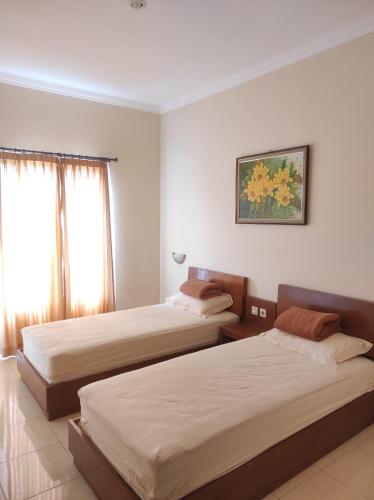 ein Hotelzimmer mit 2 Betten und einem Fenster in der Unterkunft Adiputra Guesthouse Tata Bumi in Ngabean