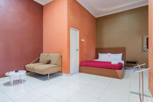 a bedroom with a bed and a chair at Hotel Markoni Pamanukan Mitra RedDoorz in Pamanukan-hilir