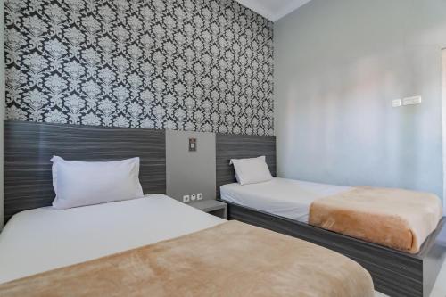 a room with two beds and a wall at Hotel Markoni Pamanukan Mitra RedDoorz in Pamanukan-hilir