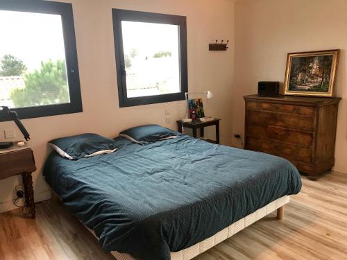 1 dormitorio con 1 cama con sábanas azules y 2 ventanas en Villa 12 PERS - PISCINE, en Les Sables-dʼOlonne
