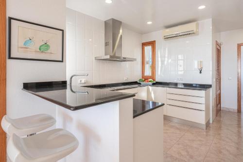 a kitchen with black counter tops and white cabinets at Vista Mar y Tierra in Marratxí 