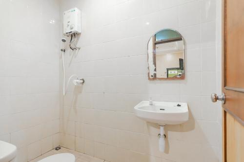 a white bathroom with a sink and a mirror at Hotel Markoni Pamanukan Mitra RedDoorz in Pamanukan-hilir