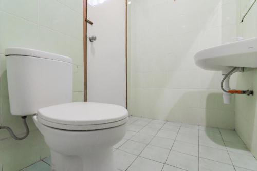 a white bathroom with a toilet and a sink at Hotel Markoni Pamanukan Mitra RedDoorz in Pamanukan-hilir