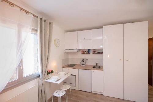 une cuisine avec des armoires blanches et une table et des chaises dans l'établissement Petit Quai - Studio entièrement rénové plein centre Trouville, à Trouville-sur-Mer