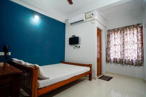 a bedroom with a bed and a blue wall at Reach Residency in Cochin