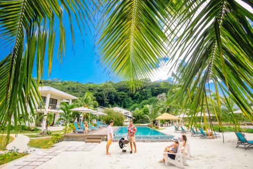 a group of people playing on the beach at a resort at Pineapple Beach Villas in Baie Lazare Mahé
