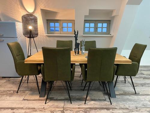 a dining room with a wooden table and green chairs at Alter Kornspeicher in Havelberg