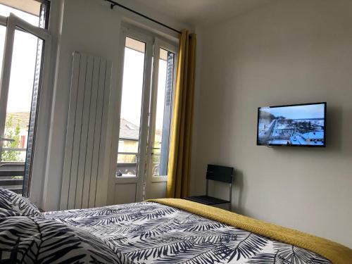 a bedroom with a bed and a television on a wall at La maison d’Alice in Aix-les-Bains