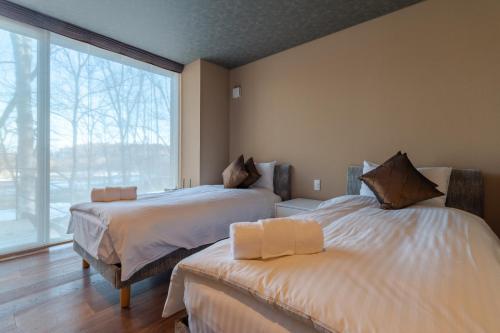 a bedroom with two beds and a large window at Hideaway on Escarpment by H2 Life in Niseko