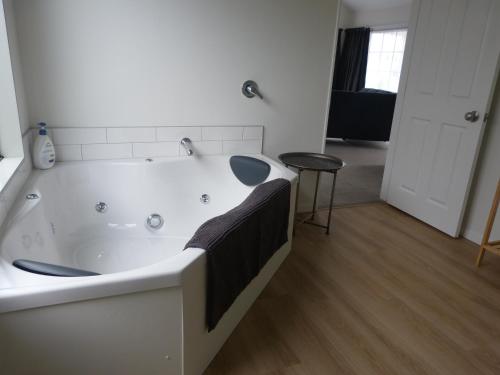 a white bath tub with a black towel on it at Blake Court Motel in Whangamata
