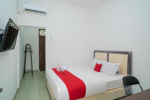 1 dormitorio con 1 cama con manta roja y blanca en RedDoorz near Bundaran Ciceri, en Kumprung