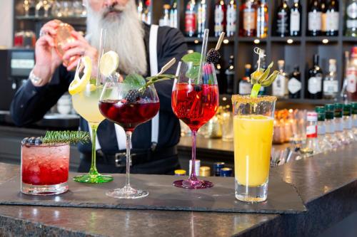 a man sitting at a bar with four different cocktails at Hotel St. Florian in Frauenau