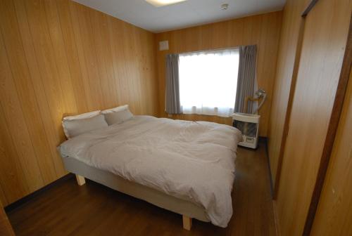 1 dormitorio con 1 cama grande y ventana en Tarochan House, en Engaru