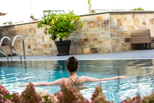 a woman sitting in a swimming pool at Hotel St. Florian in Frauenau