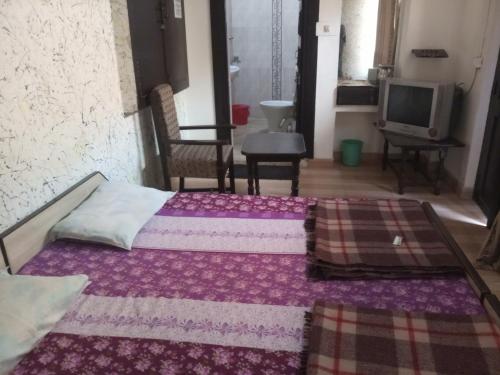 a bedroom with two beds and a tv in it at Sai Palace in Agra