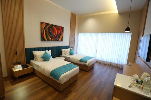 a hotel room with two beds and a window at Hotel Blueivy Anand in Anand