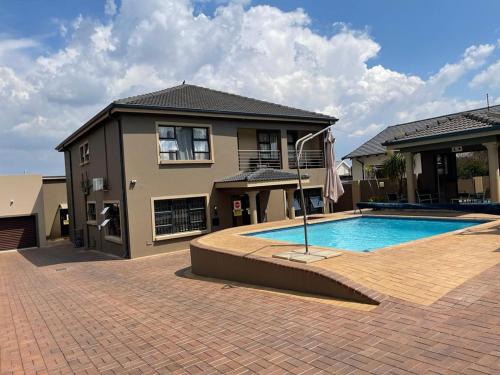 a house with a swimming pool in front of a house at Thokomala Guest House in Germiston