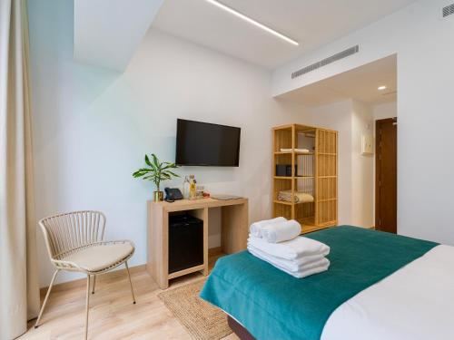 una camera con letto, sedia e televisore di Hotel Emeté & Coworking a Las Palmas de Gran Canaria