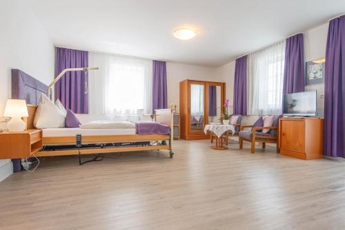 a bedroom with purple curtains and a bed and a couch at Hotel Garni Lichtquelle in Bad Füssing