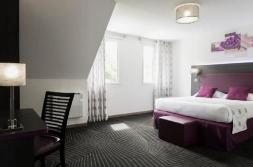um quarto de hotel com uma cama, uma secretária e uma janela em The Originals City Hôtel, Aéroport Beauvais (ex: Inter-Hotel) em Beauvais
