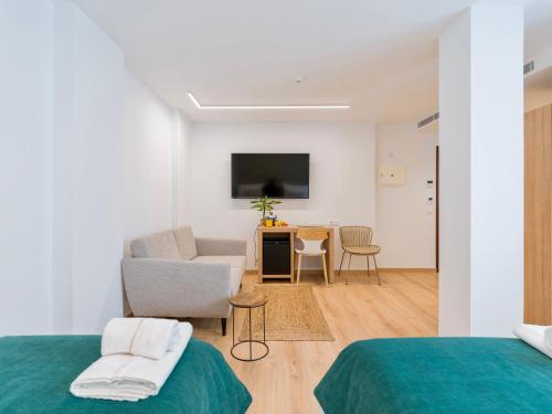 a room with two beds and a couch and a television at Hotel Emeté & Coworking by Airnest in Las Palmas de Gran Canaria